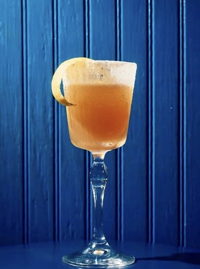Orange cocktail against a blue New Orleans bar backdrop